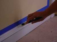 using a bursh to paint over masking tape on the walls