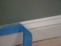 pulling masking tape off a baseboard