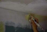 brushing paint on a wall