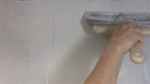 photo skimming joint compound along the edge of a drywall butt joint