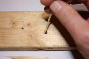 photo inserting a toothpick covered with wood glue into a hole in wood