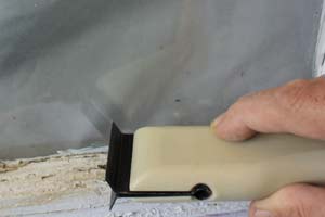 photo scraping peeling paint off a window sash