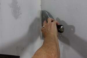 photo smoothing joint compound edges on an inside drywall corner