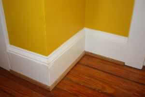 photo of a white baseboard with oak shoe molding