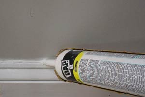 photo demonstration of caulking a baseboard cap molding