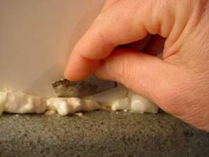 photo cutting away excess expanding foam from a crack photo cutting away excess expanding foam from a crack