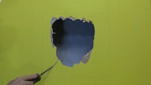 photo cutting out a drywall hole with a saw photo cutting out a drywall hole with a saw