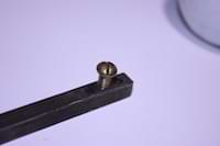 photo of a brass screw threaded into a door handle spindle photo of a brass screw threaded into a door handle spindle