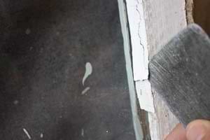 photo popping old glazing off a window glass pane with a putty knife photo popping old glazing off a window glass pane with a putty knife